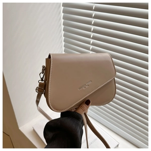 Detail of beige saddle bag with curved flap featuring Fashion Trend embossed text