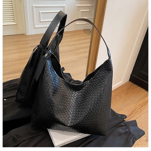 Detailed close-up of a large black woven leather tote bag showing intricate grid texture