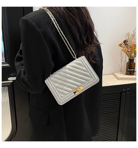Lifestyle view of a silver quilted crossbody bag with gold chain strap on a model
