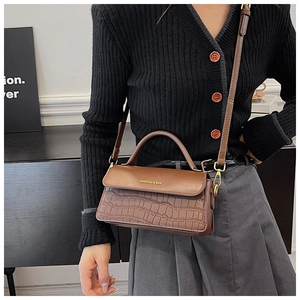 Detailed shot of brown crocodile pattern handbag with golden Fashion logo text