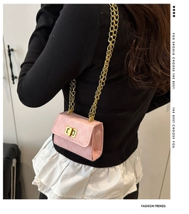 Close-up of pink mini crossbody bag with gold chain strap worn by model from behind