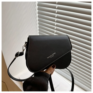 Detailed close-up of a black matte leather saddle bag with silver fashion trend lettering