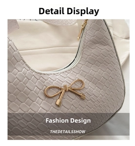 Close-up of white croc-effect leather underarm bag with gold bow-knot metal hardware