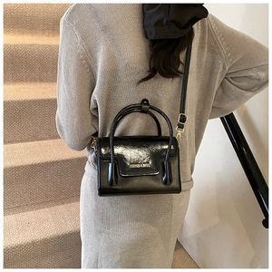 Détail d'un sac bandoulière en cuir verni noir avec lettrage doré Fashion & Bags
