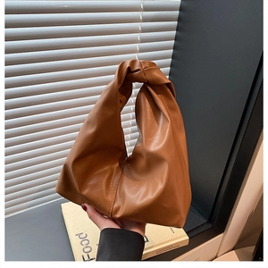 Detail of caramel pleated hobo bag with soft leather texture and single top handle