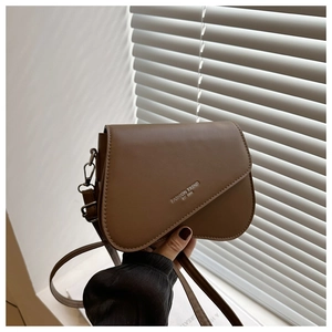Detail of a brown leather saddle bag with Fashion Trend Est 1996 text and silver hardware