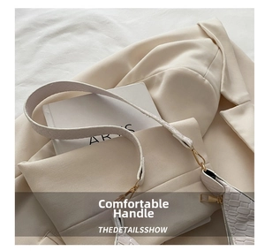 Detail of wide shoulder strap and crocodile embossed faux leather on cream white bag