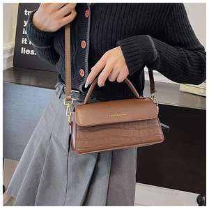 Detail of brown stone-patterned handbag with gold hardware and removable shoulder strap