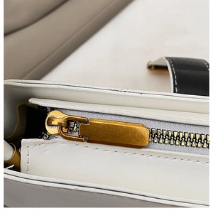Macro view of a white leather handbag featuring a vintage gold metal zipper and sleek puller