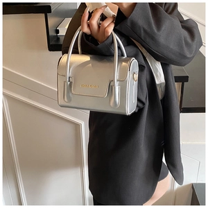 Gros plan détaillé d'un mini sac carré argenté avec logo métallique et finition polie
