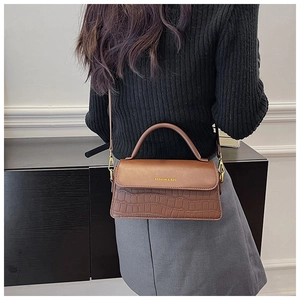 Detail of brown faux leather handbag showing crocodile texture and gold fashion logo