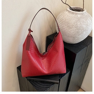 Detailed close-up of red woven leather hobo bag with intricate texture and fashion tag