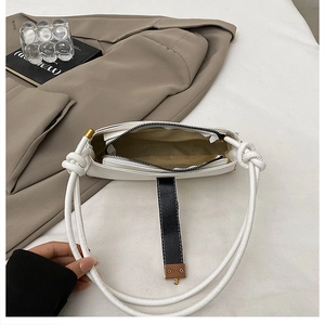 Detailed interior of white leather baguette bag with zip closure and gold metal buckle