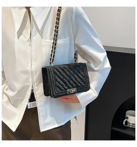 Detail of black V-quilted leather crossbody bag with chain strap and metallic lock clasp