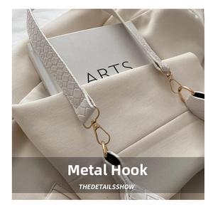 Detail of light gold hardware hook and woven shoulder strap on beige crescent bag