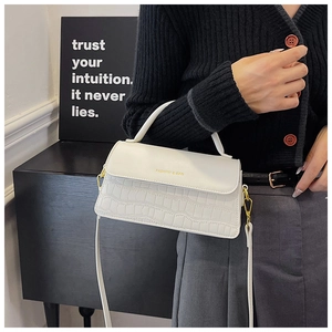 Detail of white crocodile embossed small square bag with gold hardware and logo