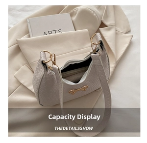 Detailed shot of beige woven shoulder bag with gold bow buckle on a beige blazer