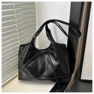 Detail shot of black PU leather tote bag with stylish bow accent and fine texture