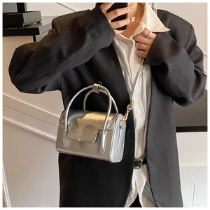 Détail du mini sac carré argenté avec poignée supérieure et bandoulière réglable