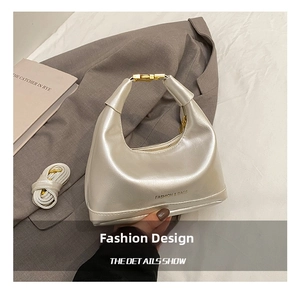 Close-up of silver crescent hobo bag with fashion text, gold buckle and accessories