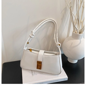 Detail of a white leather baguette bag with a vintage gold square clasp and rope strap
