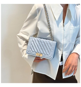 Close-up of light blue quilted leather bag with V-shaped stitching and gold chain strap
