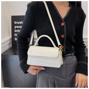 Model wearing white crocodile pattern handbag with gold hardware and logo detail