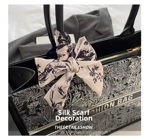 Detail of black tote bag with white embroidery pattern and decorative silk scarf bow