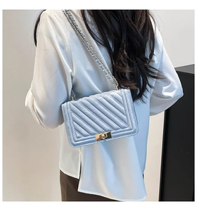 Detailed view of light blue quilted leather cross-body bag with gold chain strap