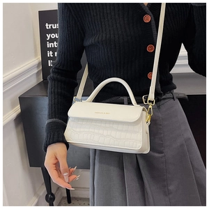 White croc-embossed leather crossbody bag shown on a model with top handle and strap