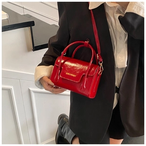 Détail du mini sac à bandoulière en cuir verni rouge brillant avec texte doré élégant