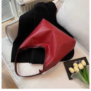 Detailed view of woven red hobo bag with Fashion embossing on a white sofa scene