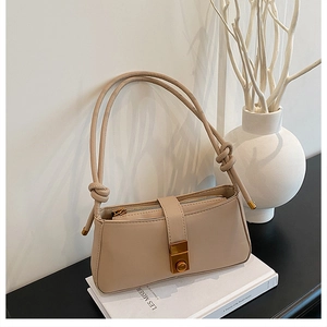 Detail of beige baguette bag showing matte leather texture, knot strap, and gold clasp