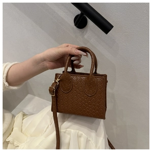 Detail of dark brown woven mini handbag featuring checkerboard texture and dual handles
