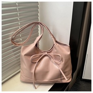 Detail of pink tote bag showing large bow knot design and soft premium leather texture