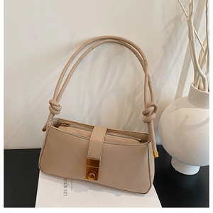 Detailed close-up of beige minimalist baguette bag with gold metal buckle and knotted strap