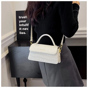 Detail of off-white stone-patterned crossbody bag with gold clasp on a model