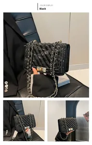 Detail of black crossbody bag with diagonal stitching, metal lock, and woven chain strap
