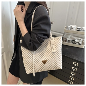 Détail du grand sac cabas à motifs ronds beiges avec poignées en cuir blanc et plaque métal
