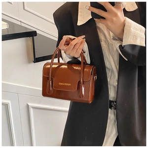 Gros plan du sac à main marron en cuir verni brillant avec texte FASHION & BAGS et anses