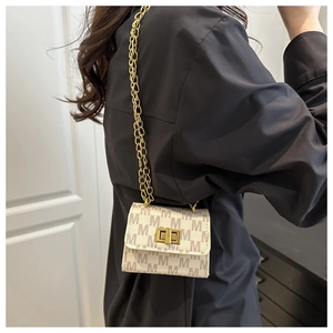 Detail of mini crossbody bag featuring golden chain strap and letter M monogram pattern