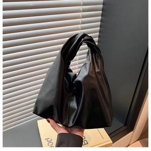 Detail of minimalist black pleated handbag with a unique knotted handle design