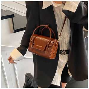 Détail d'un sac bandoulière vintage marron avec texte imprimé et poignée incurvée