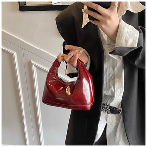 Close-up of a burgundy oil wax leather crescent bag with gold logo and top handle