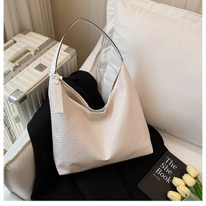 Detail of white crocodile embossed leather tote bag with fashion tag on a black fabric