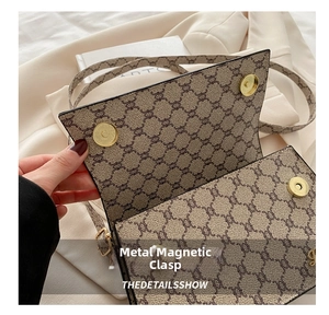 Détail d'un sac carré rétro en toile avec fermoirs magnétiques dorés et motifs imprimés