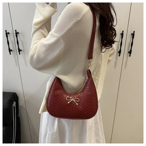 Detail of burgundy woven hobo bag with a golden bow buckle and slim shoulder strap
