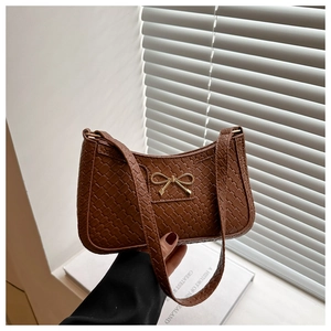 Detailed close-up of brown woven texture handbag with a golden metal bow accessory