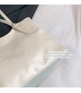 Detail of soft cream white tote bag featuring micro-wrinkle texture and silver buckle