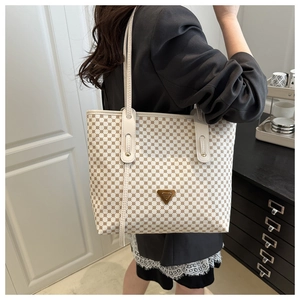Détail d'un grand sac cabas beige à pois marrons avec logo triangulaire en métal